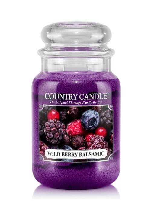 En lila doftljus i glas med etikett av bär och namnet "Wild Berry Balsamic".