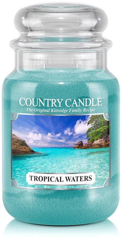 Ett glaskrus med lock som innehåller ljusgult vax i turkos blå färg, märkt 'Country Candle' och 'Tropical Waters', med en strandbild.