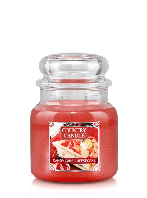 Eldfärgad ljus i glasburk med etikett 'Candy Cane Cheesecake' och festlig design.