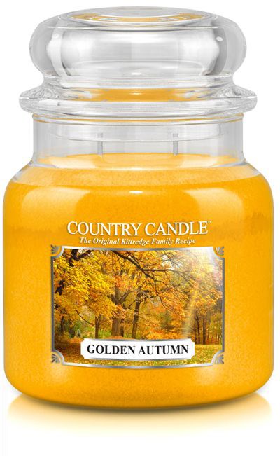 Ett gult ljus i glasburk märkt 'Golden Autumn' med höstträd i bakgrunden.