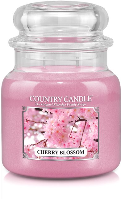 Ett rosa ljus i ett glas med bilder av körsbärsblomma och etikett. Det står 'Cherry Blossom'.