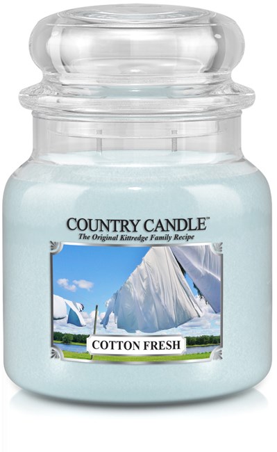 Vitt ljus i ett glas med etikett med segelbåtar och texten 'Cotton Fresh' och 'Country Candle.'
