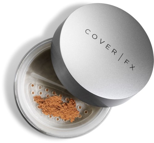 En rund behållare med lock med texten 'COVER FX' som innehåller lös brun puder på en perforerad yta.