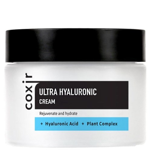 Valkoinen purkki mustalla kannella, jossa lukee "Coxir Ultra Hyaluronic Cream" ja sisältää hyaluronihappoa ja kasviproteiinia, kosteuttaa ihoa.