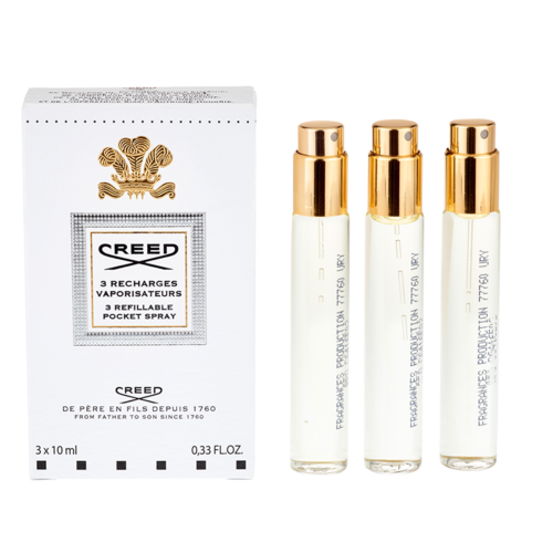 Tre små parfyymflaskor med guldkapslar och en vit box märkt 'Creed' för påfyllningsbar fickspray.
