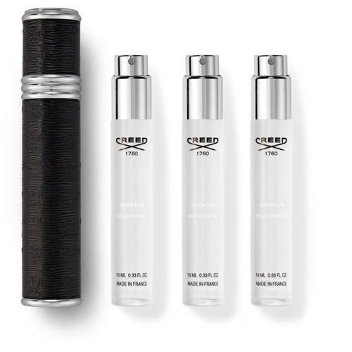 En svart och silver behållare bredvid tre vita sprayflaskor märkta Creed Aventus. Enkel och ren layout.