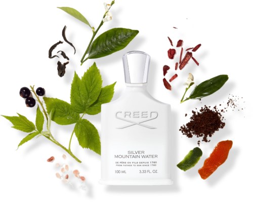 En flaska Creed Silver Mountain Water parfym omgiven av gröna blad, bär, en chili, kryddor och ett pulver.
