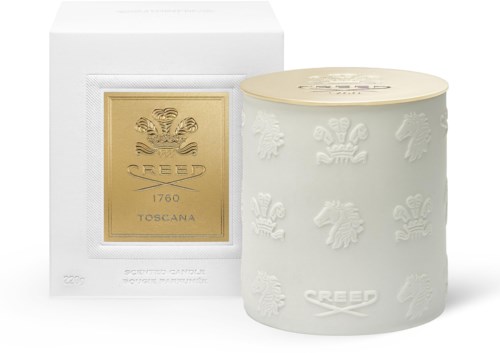 En vit ljuslykta med upphöjda lejon- och vapensköldsdetaljer, bredvid en guld- och vit låda med Creed-logotyp.