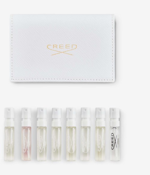 En hvit boks med gull CREED-logo og sju små parfymetestflasker under.