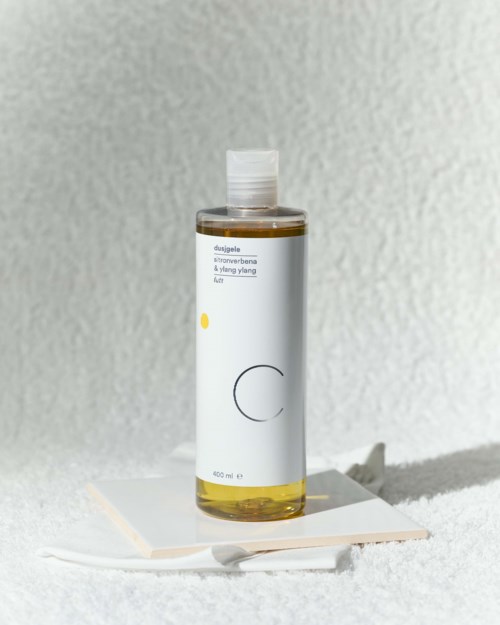 A tall, clear bottle with a white label and flip-top cap, standing on a white paper on a textured surface.