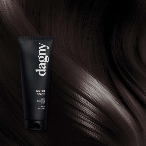 A black tube of Dagy outer space color depositing mask lies on shiny dark brown hair.