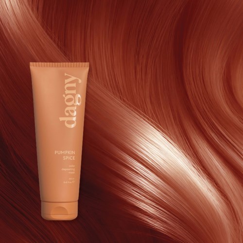 A tube of pumpkin spice hair dye in front of flowing shiny red hair. The tube has the word "dawg" on it.