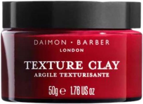 Rød krukke med svart lokk, merket 'Daimon Barber Texture Clay,' veier 50g, for styling av hår.