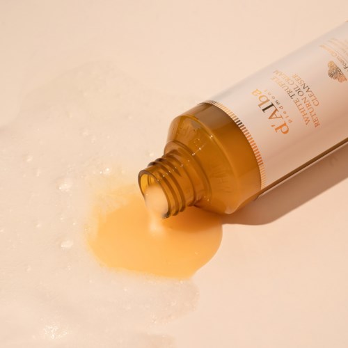 Eine Tube Hautcreme läuft auf eine Oberfläche, mit etwas Flüssigkeit darum herum.