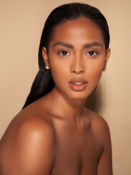 A woman with smooth dark hair, glowing skin, and elegant earrings, looking confidently at the camera.
