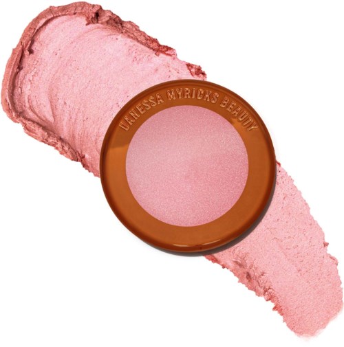 A round makeup product with brown edges and pink powder inside, labeled with a brand name. Cremes and powder around it.