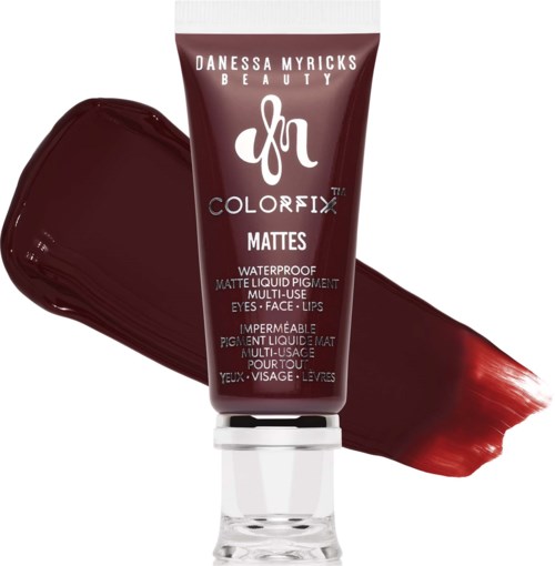 En mørkerød tube med Danessa Myricks Beauty Colorfix Matte vandtæt flydende pigment ved siden af en stribe med dybrød læbestift.