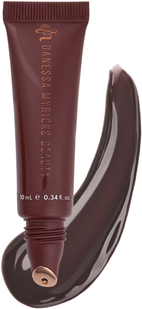 A brown tube of Danielaska Myricks Beauty product with a swatch of dark lipstick or balm.