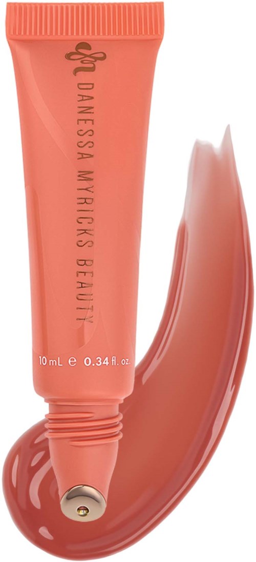 Coral-colored tube of skincare or cosmetic product with a swatch of product next to it.