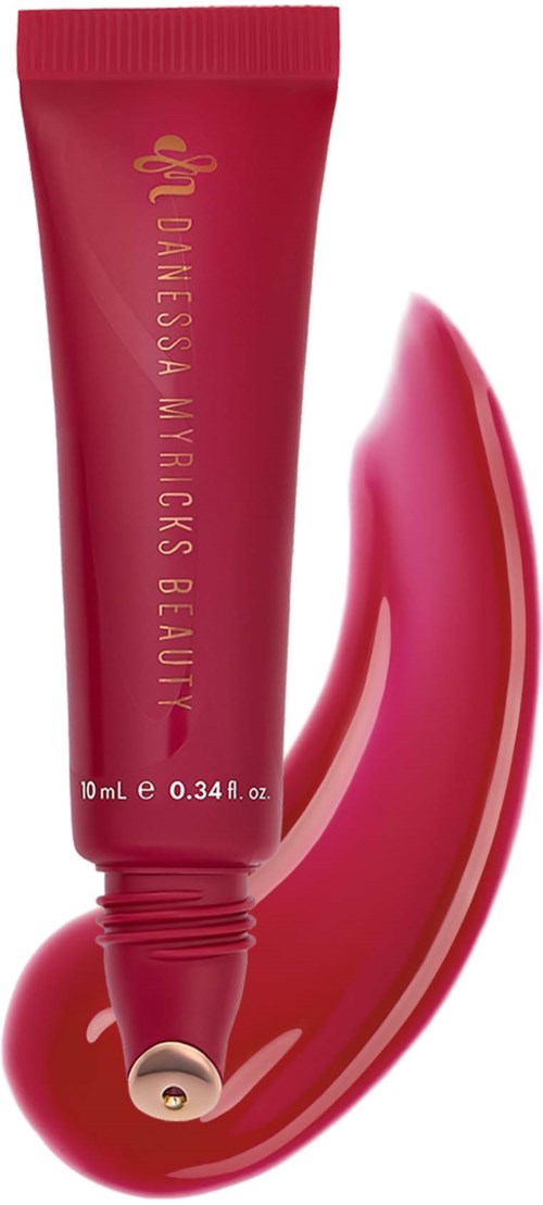 A pink tube of skincare product with gold lettering and a metallic gold cap, with product swatch underneath.