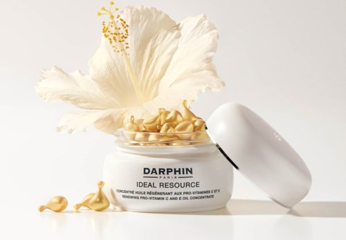 Ein Behälter mit Hautpflegecreme mit einer großen weißen Blume dahinter und etwas Creme drumherum.