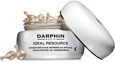 En krukke med Darphin ungdomsretinololje med lokk, som viser gullfargede kapsler og hvit krem inni.