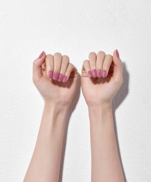 Two hands with pink painted nails are raised, clenched into fists, against a plain white background.