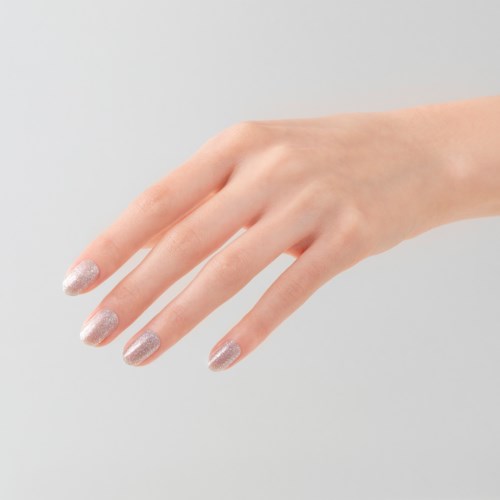 A hand with long fingers and silver glittery nail polish on each fingernail.