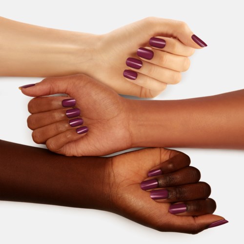 Three hands with purple nail polish are stacked, showing diversity in skin tones.