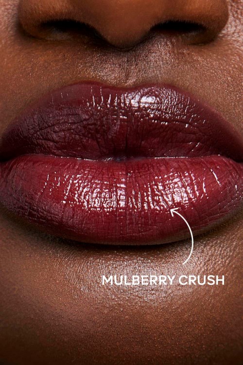 Close-up of lips with glossy, dark lipstick. The label says "Mulberry Crush" on the lips.