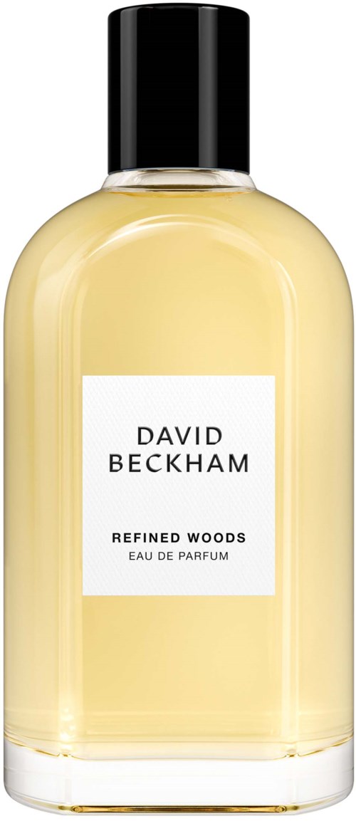 Een parfumfles met een wit label dat zegt 'DAVID BECKHAM REFINED WOODS'. De fles is doorzichtig met lichtgele geur.