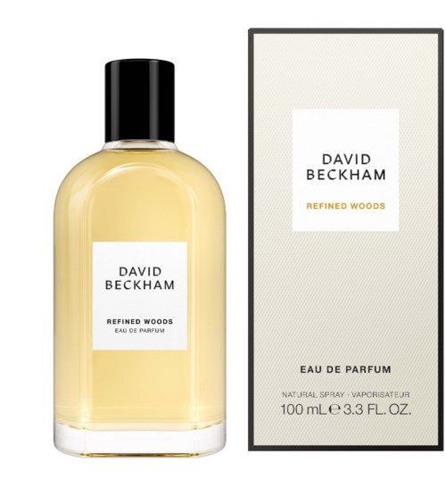 Een parfumfles en doos gemerkt 'David Beckham Refined Woods'. De fles is doorschijnend met gele vloeistof en een zwarte dop.