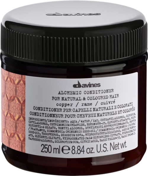 A jar of Davines Alchemic Conditioner for natural and colored hair, with a black lid and a label showing details.