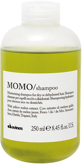 En grøn flaske med MOMO-shampoo til tørt eller beskadiget hår, med hvid etiket og sort tekst.