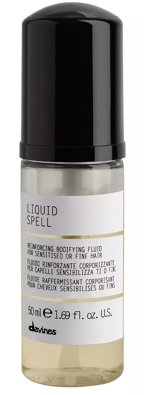 En liten flaske med sorte lokk og hvit etiket. Etiketten sier "Liquid Spell" og nevner styrking for følsomt eller fint hår.
