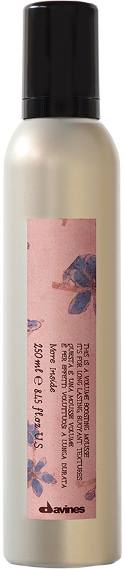 En vit sprayflaska med svart lock och en rosa etikett med blå och lila mönster.