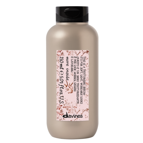 A small beige bottle with a black flip cap and a label with red plant-like designs and text.