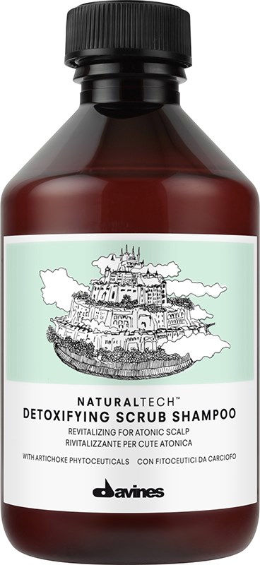 En brun flaske med sort låg, etiketten viser en slottegn og tekst om afgiftende scrubshampoo.