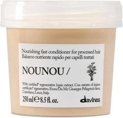 En beige plastburk med vitt lock, etikett visar produktnamn, storlek och ingredienser för hårbalsam.