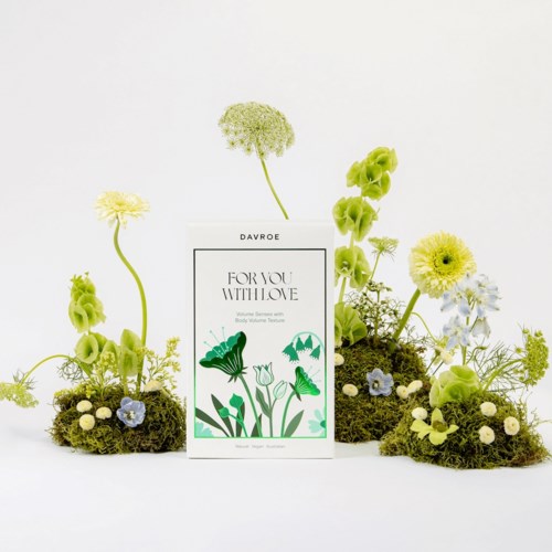 En låda med gröna och gula blommor arrangerade runt den på en enfärgad vit bakgrund.