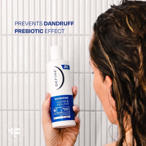 A woman holding a white and blue shampoo bottle with text that promotes dandruff prevention and a healthy scalp.