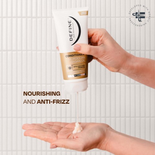 A hand holds a white and gold tube of conditioner titled 'Define Moroccanoil' above an open palm with product.