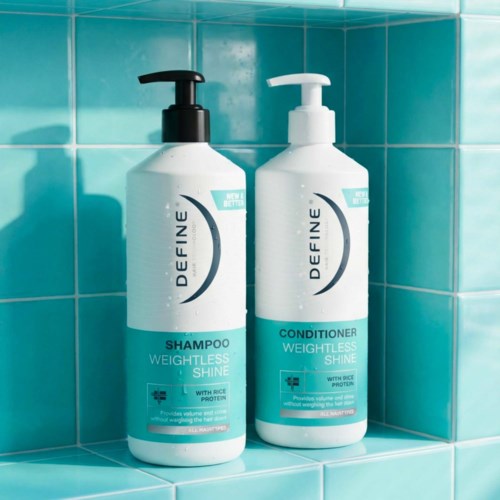 To hvide flasker med shampoo og balsam med sorte og hvide låg står på en lys turkis fliseoverflade.