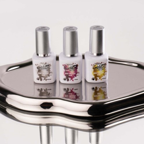 Three bottles of nail gel polish with different colors on a shiny silver surface.