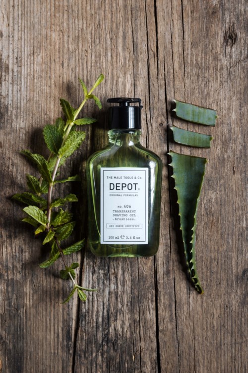 En grön flaska med DEPOT rakgel, gröna aloe vera-blad och ett grönt aloeblad på en träyta.