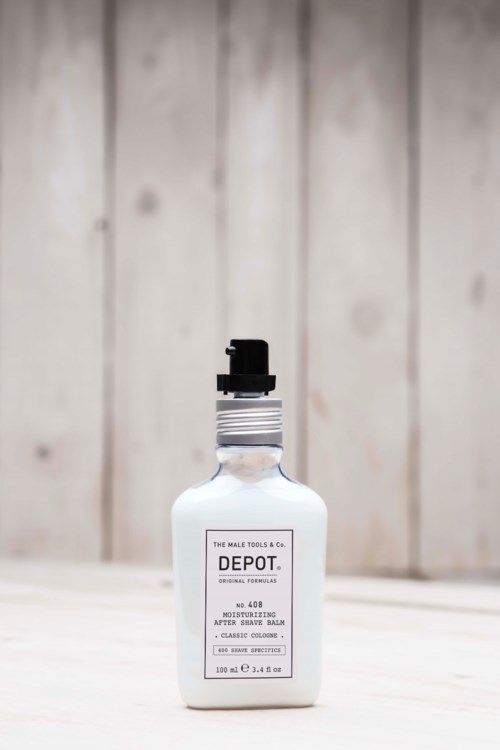 En vit flaska med svart lock märkt 'The Male Tool & Co. DEPOT'. Den står på en ljus träyta.