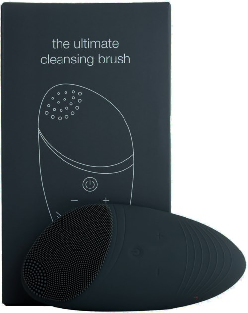 En svart rengöringsborste formad som en oval, med en texturerad yta, placerad framför en låda märkt 'the ultimate cleansing brush.'