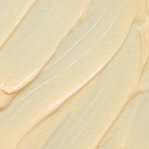 Krämfärgad substans utbredd jämnt i diagonala linjer. Ser mjuk och rik ut, kanske smör eller frosting.