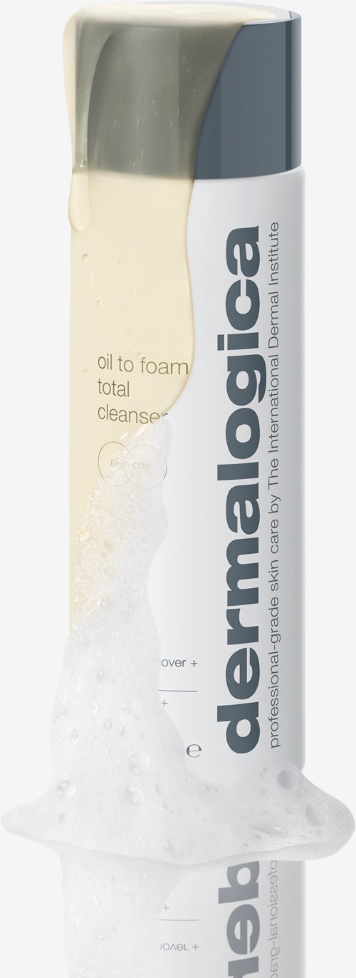 A white and gray bottle is pouring white foam, labeled 'dermalogica' and 'oil to foam total cleanse'.