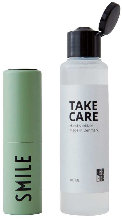 A green lipstick container labeled "SMILE" and a clear hand sanitizer bottle labeled "TAKE CARE."
